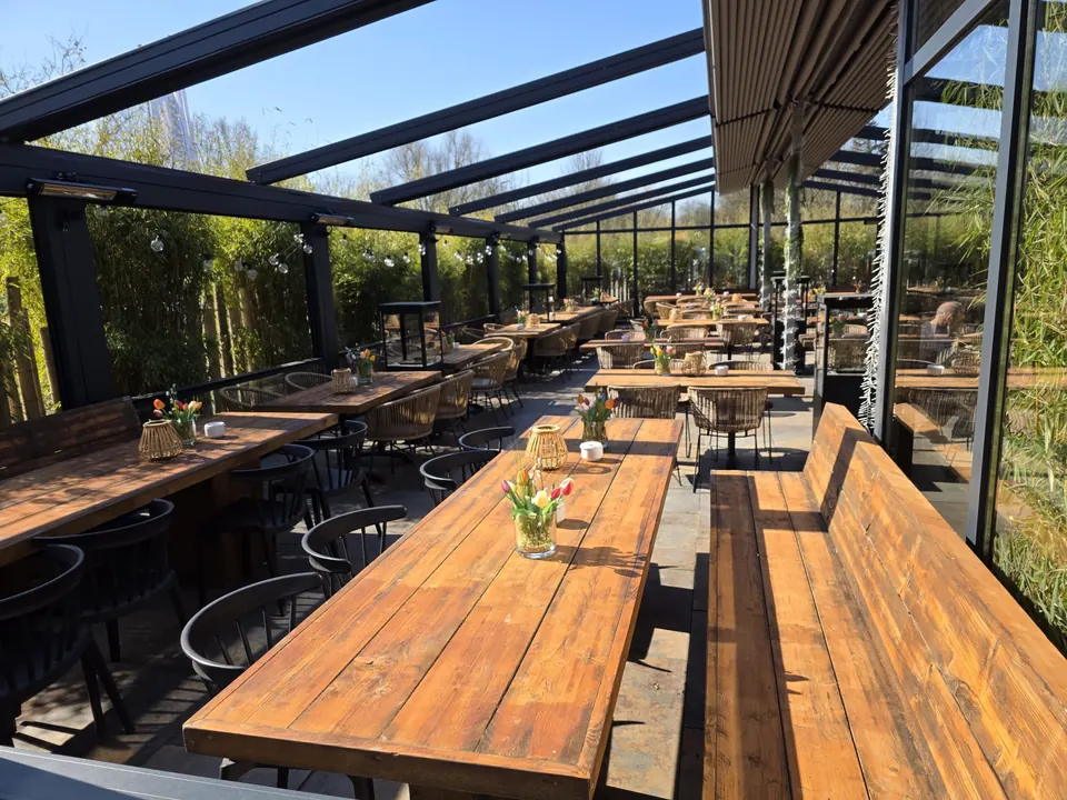 Holztische unter dem Glasdach des Wintergartens am Restaurant 28 Süd in Duisburg